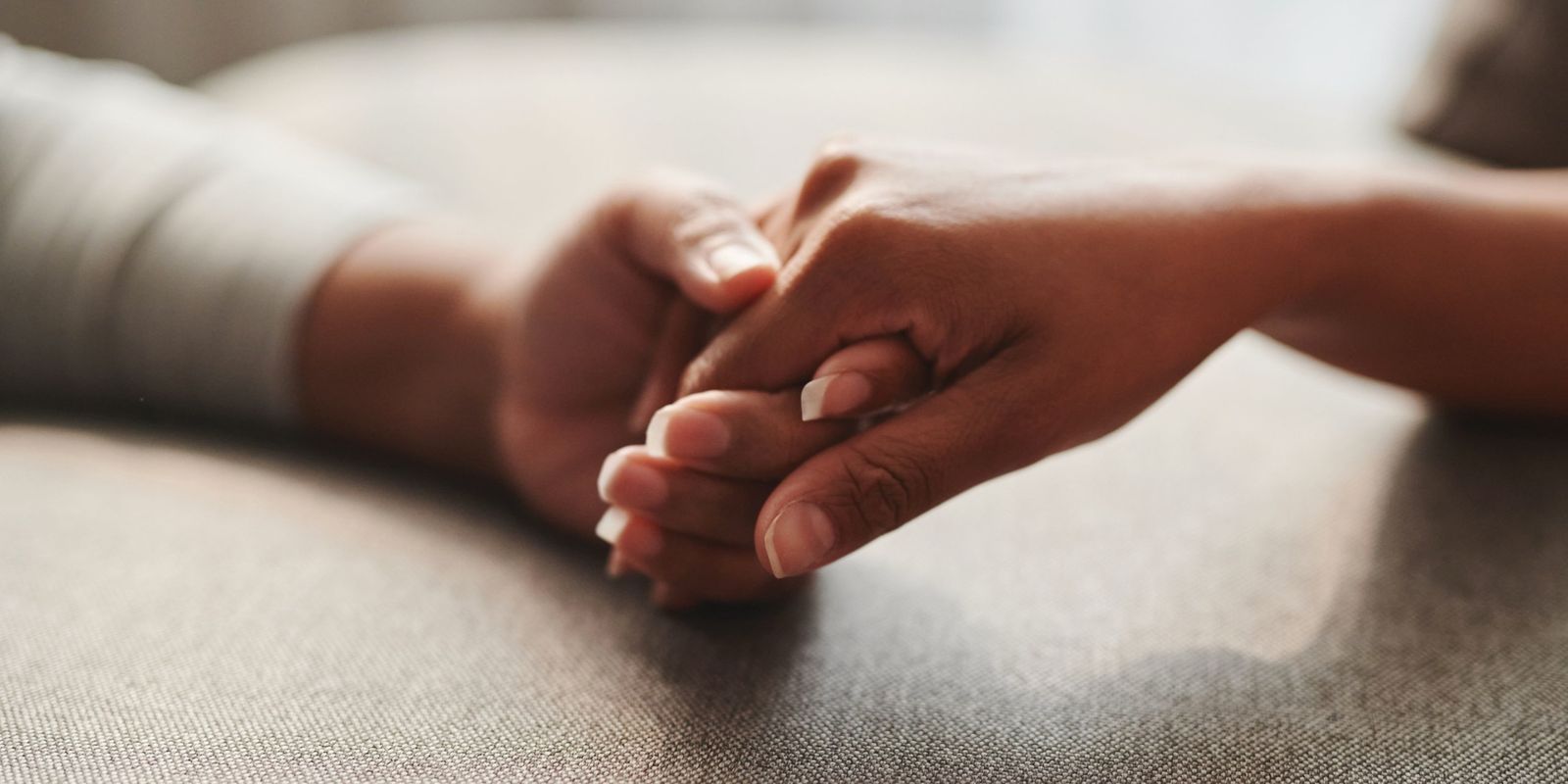 Two people holding hands, resting on a table in soft light